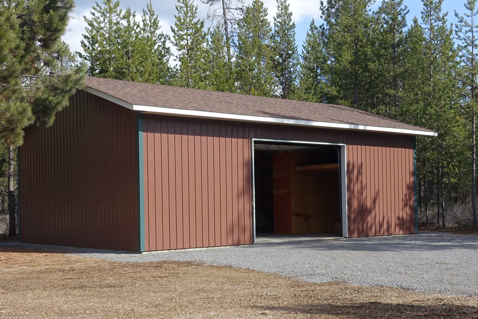 Building sheathed in red steel with large central rollup door.